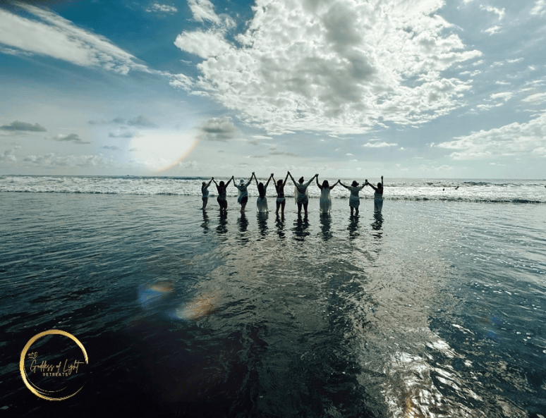 Women standing in the ocean with arms raised